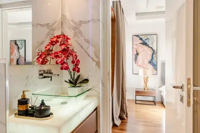 a bathroom with a glass sink and red flowers on a counter at Beachfront Luxury Apartment in Limassol