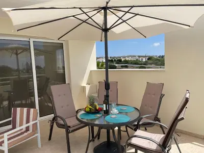 a table and chairs with an umbrella on a patio at Nissi Beach sunny cozy apartment in Ayia Napa