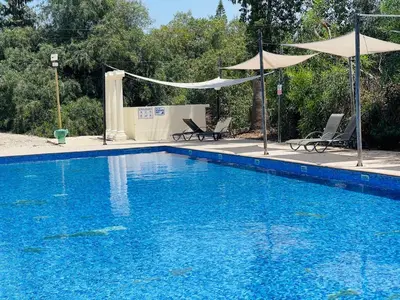 a large blue swimming pool with two chairs and umbrellas at Nissi Beach sunny cozy apartment in Ayia Napa