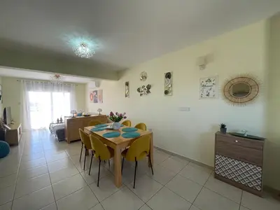 a dining room with a table and yellow chairs at Nissi Beach sunny cozy apartment in Ayia Napa