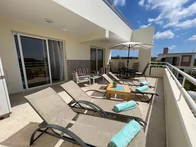 a patio with chairs and an umbrella on a balcony at Nissi Beach sunny cozy apartment in Ayia Napa
