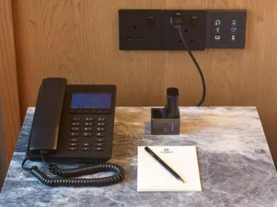 a desk with a phone and a pen and a notebook at Pendeli Resort in Platres
