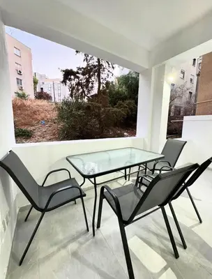 three chairs and a glass table on a balcony at Modern One-Bedroom Suite with Balcony in Central Nicosia in Nicosia
