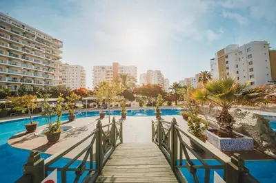 a wooden walkway leading to a swimming pool with buildings at CAESAR RESORT İSKELE Long Beach in Vrysoules
