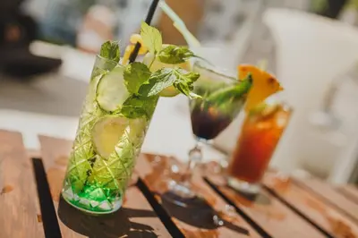 two cocktails sitting on a wooden table with drinks at CAESAR RESORT İSKELE Long Beach in Vrysoules