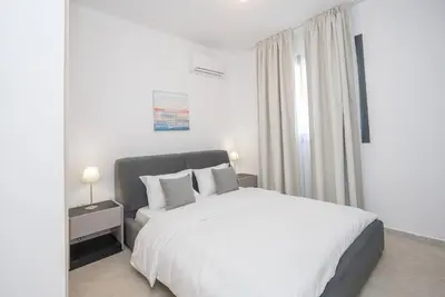 a white bedroom with a bed and a window at Kalamon Luxury Suite 202 w Pool and Gym in Larnaka