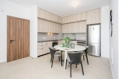a kitchen with a table and chairs and a refrigerator at Kalamon Luxury Suite 202 w Pool and Gym in Larnaka