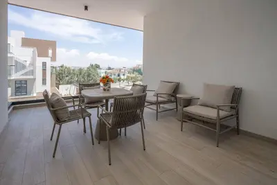 a dining room with a table and chairs and a large window at Kalamon Luxury Suite 202 w Pool and Gym in Larnaka