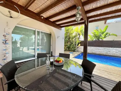 a dining room with a table and chairs and a pool at STAY Thalassa Villa in Paralimni