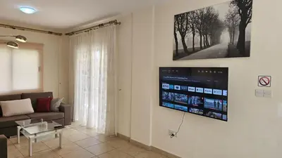 a living room with a couch and a tv on the wall at STAY Nissi House in Ayia Napa