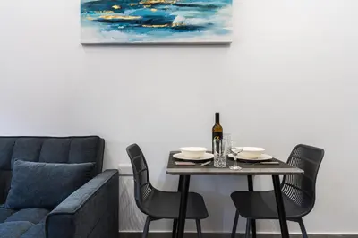 a dining room table with a bottle of wine and a couch at Le Bandit Studio in Larnaka