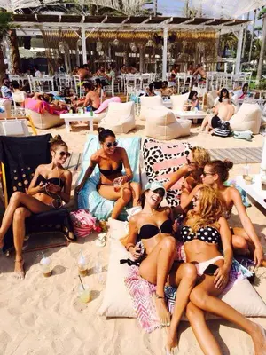 a group of women in bathing suits sitting on the beach at Dome Beach Marina Hotel & Resort in Ayia Napa