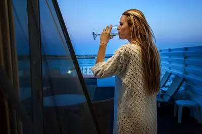 a woman standing on a balcony holding a plane at Dome Beach Marina Hotel & Resort in Ayia Napa