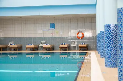 a swimming pool with tables and chairs next to it at Constantinos the Great Beach Hotel in Protaras