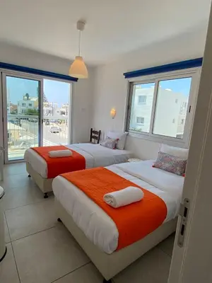 two beds in a hotel room with windows at Mangoes & Cherries in Ayia Napa