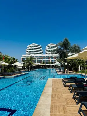 a swimming pool with chairs and buildings in the background at Wakacyjny apartament w Courtyard Long Beach Holiday Resort in Iskele