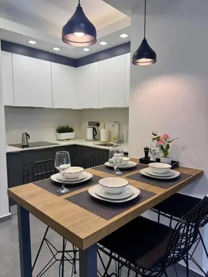 a kitchen with a wooden table with plates and wine glasses at Wakacyjny apartament w Courtyard Long Beach Holiday Resort in Iskele