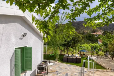 a white house with green doors and a yard at Galata Watermill Cottage in Nicosia