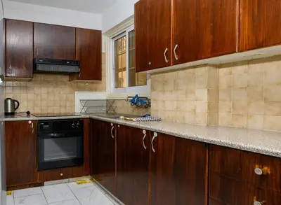 a kitchen with wooden cabinets and a black dishwasher at Martin 2 bed Apartment in Larnaka