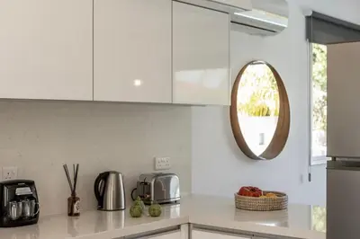 a kitchen with white cabinets and a mirror at Sam's Villa in Paralimni