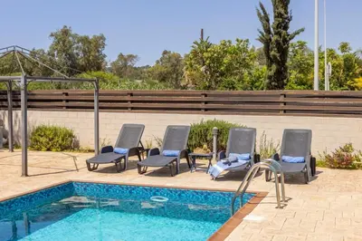 a pool with four lounge chairs next to a swimming pool at Villa Parrog in Protaras