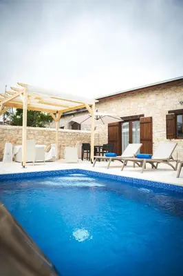 a swimming pool with chairs and a pavilion at Althaea Mare in Lofou