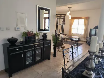 a living room with a black dresser and a mirror at Ambelli Villa 4 Bedroom Luxury Villa in Skarinou