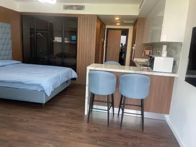 a bedroom with a bed and a kitchen with two bar stools at Grand Sapphire Resort in Aglantzia