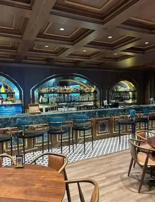 a restaurant with a bar with blue chairs and tables at Grand Sapphire Resort in Aglantzia
