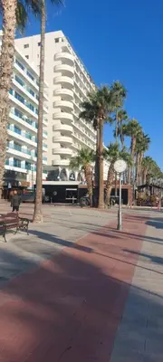a large white building with palm trees in front of it at 3 Bedroom Apartment Old Town Larnaca 5 minute walk to Finnikoudes Beach in Larnaka