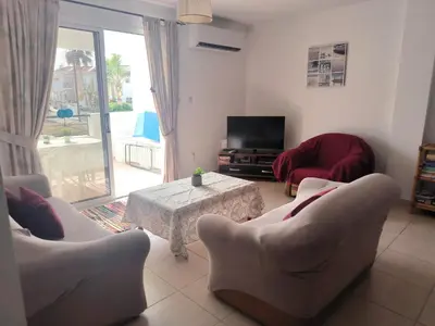 a living room with chairs and a table and a television at 3 Bedroom Affordable Apartment in Oroklini with Communal Pool in Voroklini