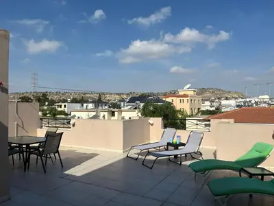 a patio with chairs and tables on a roof at 2 Bedroom Penthouse Apartment in Oroklini with Communal Pool in Voroklini