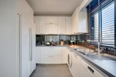 a white kitchen with a sink and a refrigerator at Makenzy Star 2bd duplex 300m from beach in Larnaka