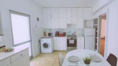 a kitchen with white cabinets and a table and a washer at STAY Virtuoso Apartment in Nicosia