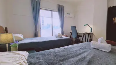 a bedroom with two beds and a desk and a window at STAY Virtuoso Apartment in Nicosia
