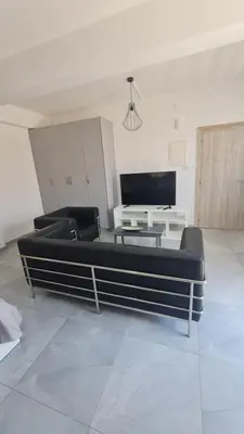 a living room with a black couch and a tv at RIVERA Studios 1 in Limassol