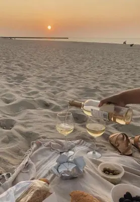 a person pouring wine into two glasses on the beach at Family large apartment in Bahçeli in Aglantzia