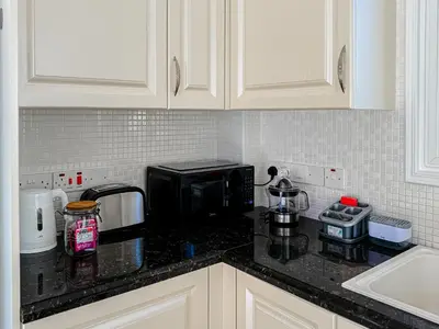 a kitchen with a black counter top with a microwave at Sunny Villa with Hot Tub, Garden and 2 Bedrooms, 5 Minutes to the Beach in Pyla