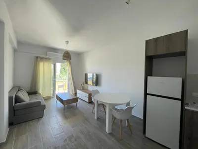 a kitchen and living room with a table and a refrigerator at Green Bay Cosy Escape in Protaras