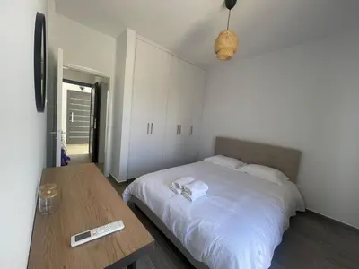 a bedroom with a white bed and a wooden table at Green Bay Cosy Escape in Protaras