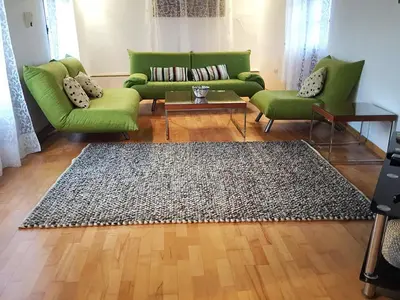 a living room with a green couch and a rug at Cobblers in Maroni