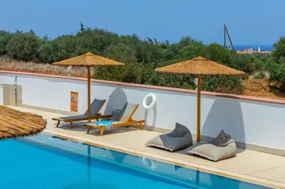a swimming pool with two chairs and umbrellas on a house at Protaras Views Villa PRAM1 in Protaras