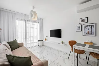 a white living room with a couch and a table at Majan Residences in Larnaka