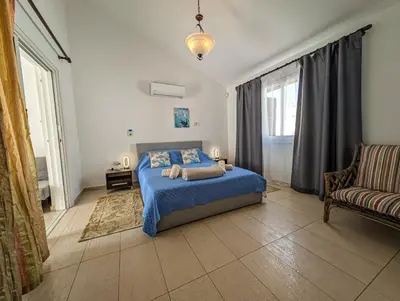 a bedroom with a blue bed and a couch at Fig Tree Bay Villa Elena in Protaras