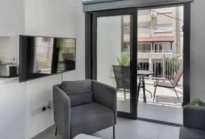 a living room with a chair and a balcony at Seabreeze Residence by Staycom in Larnaka
