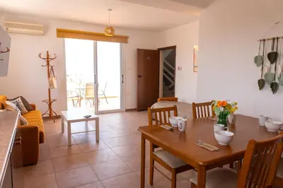a kitchen and living room with a table and chairs at STAY Kali Sun Apartment in Paralimni