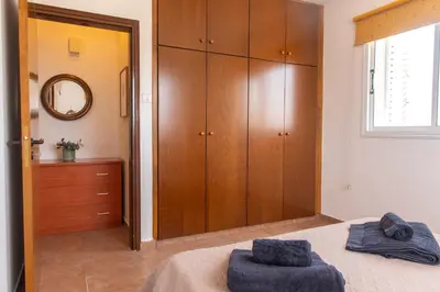 a bedroom with a bed and a wooden closet at STAY Kali Sun Apartment in Paralimni