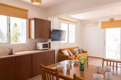 a kitchen and living room with a table and a couch at STAY Kali Sun Apartment in Paralimni