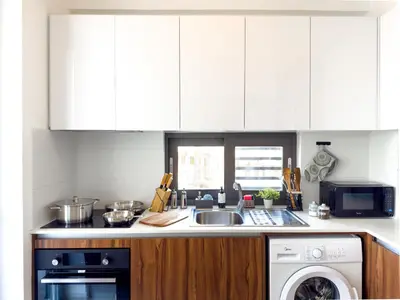 a kitchen with a sink and a washing machine at Sunset Balcony and Espresso Station Apartment in Larnaka
