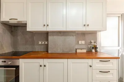 a kitchen with white cabinets and a wooden counter top at Cosy 2-Bedroom Apartment, 10 Minutes from the Beach in Larnaka